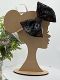 Black Nylon Headband with a decorative white and orange fireworks themed big bow on a mannequin head silhouette against a white background