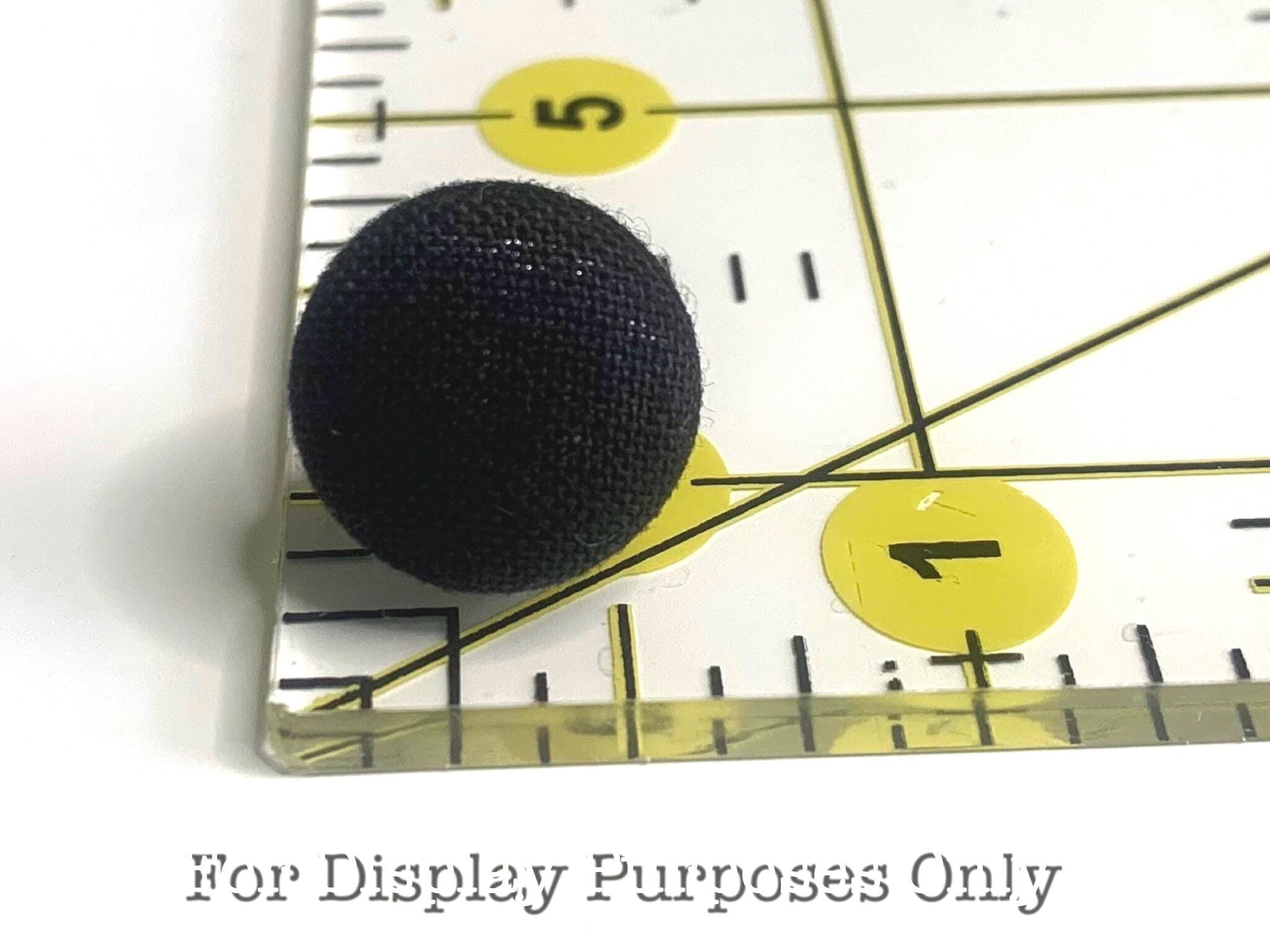Black textured earring on a ruler with measurement markings with text 'for display purposes only'