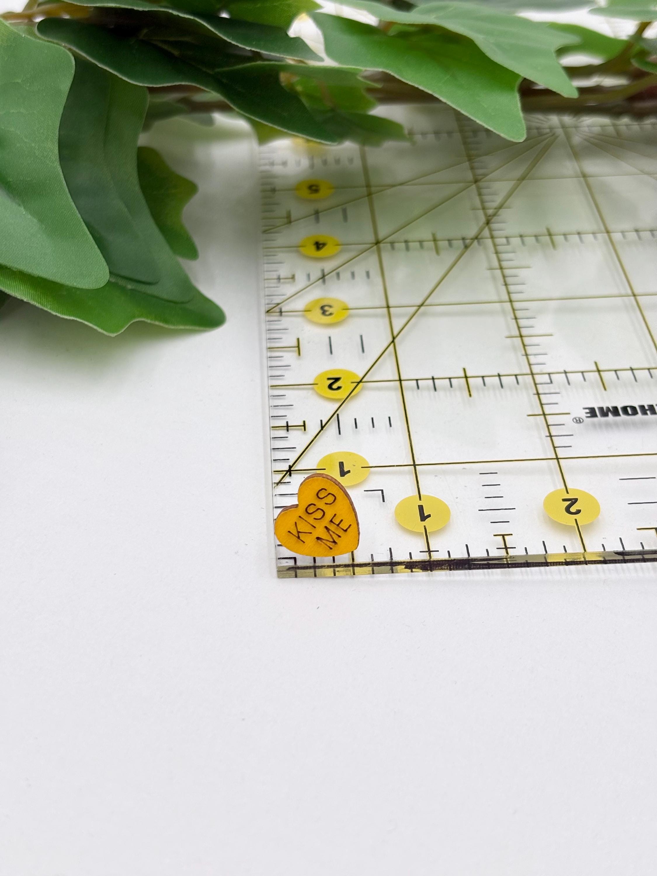 Yellow heart shaped earring on a Ruler with green leaves on a white background