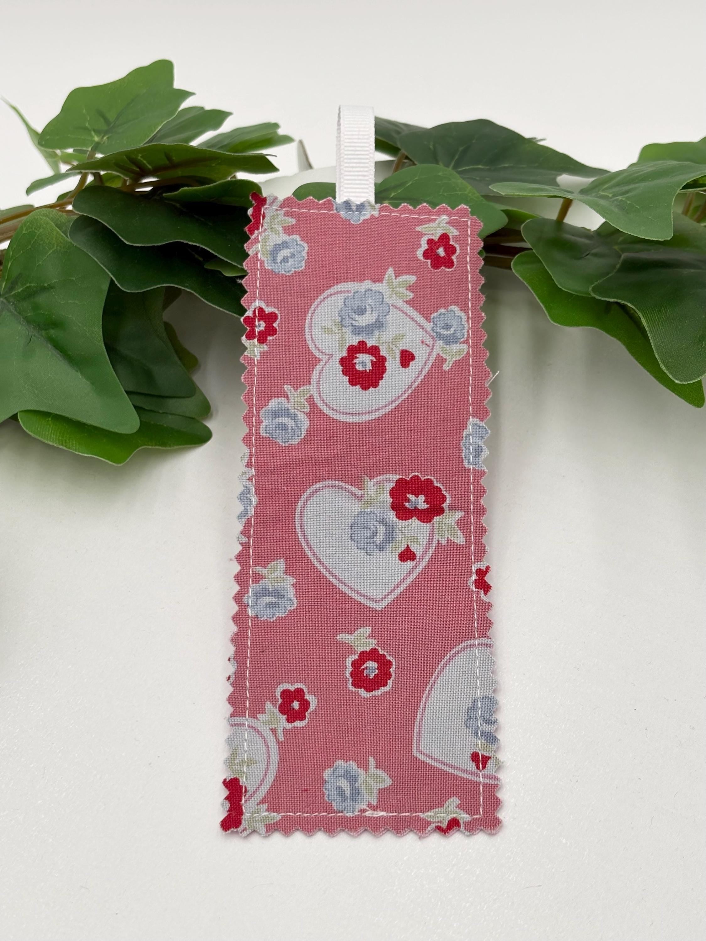Fabric bookmark with heart and flower pattern on a green plant