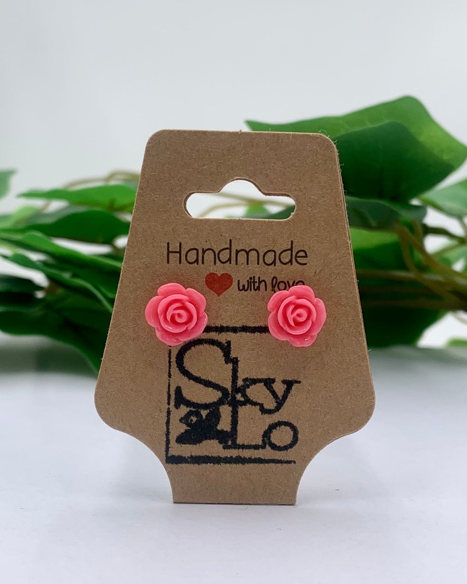 Pastel Raspberry rose-shaped earrings on a 'Handmade with Love' branded card with a green leafy background.