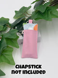 Pink easter themed chapstick holder on a white surface with green leaves in the background with text "chapstick not included"