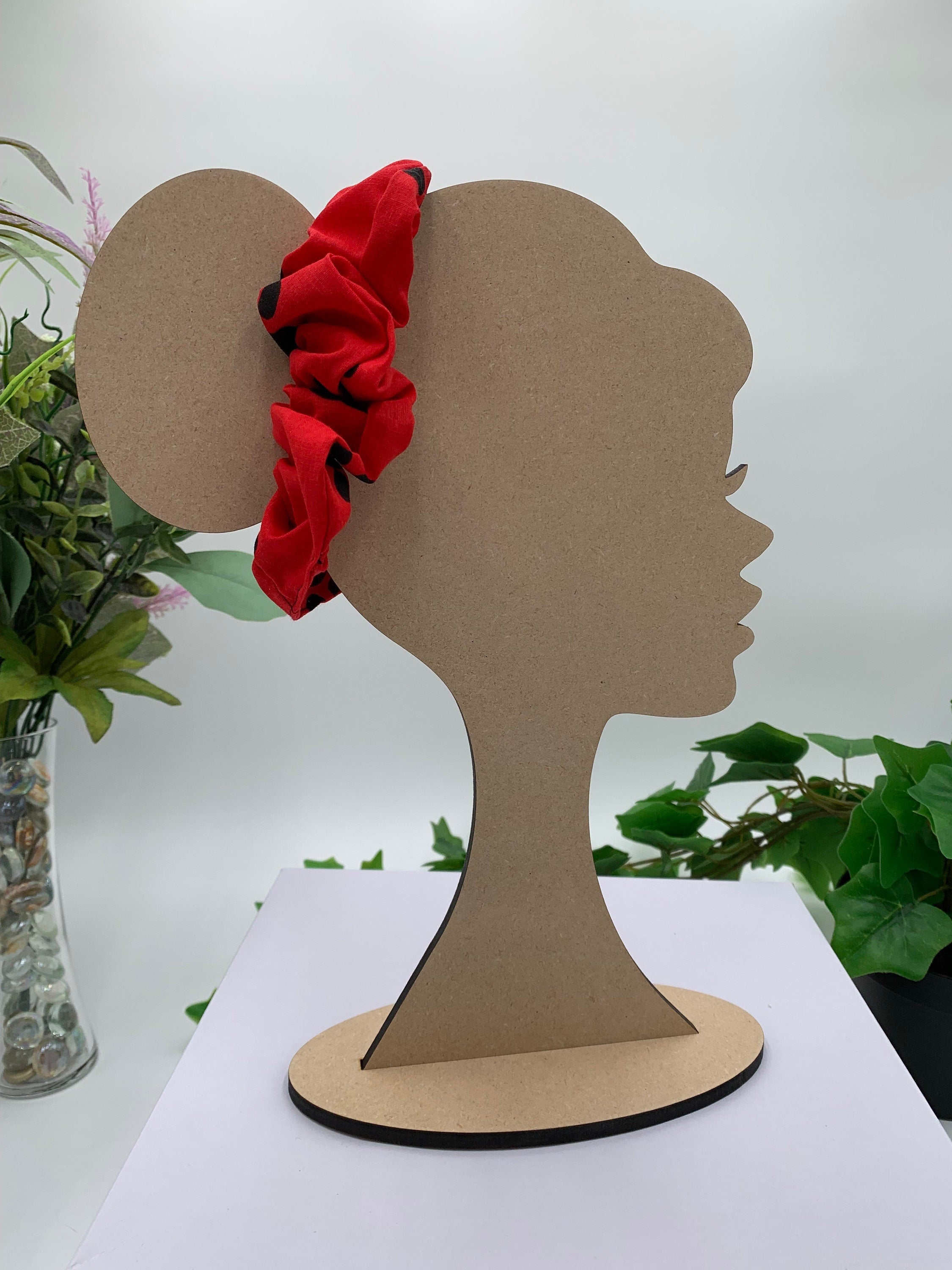 Red with black paw prints scrunchie on a cardboard silhouette of a head with plants in the background