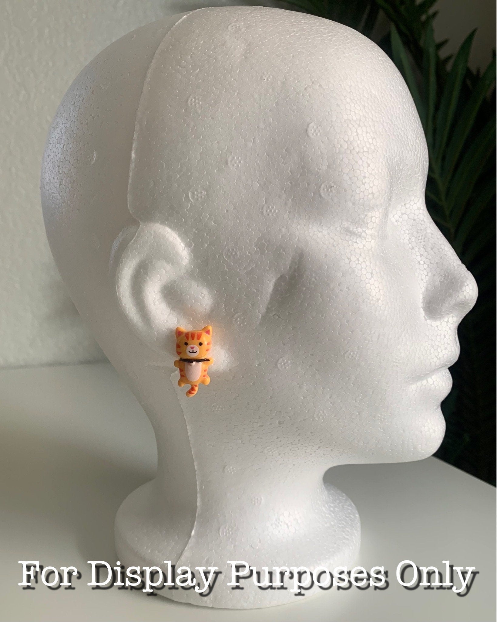 Orange cat-shaped earring on a white mannequin head with text 'For Display Purposes Only'.