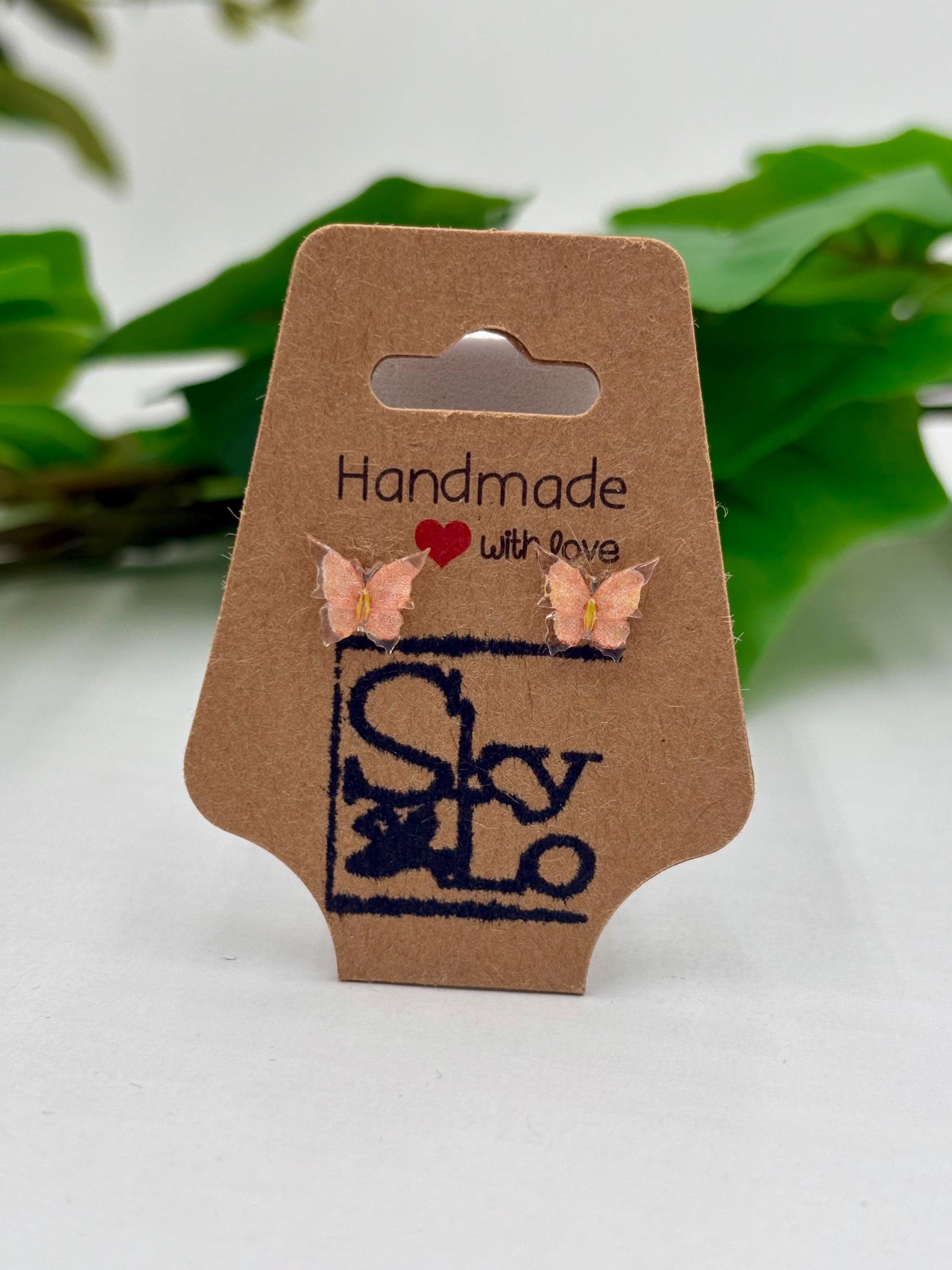 Peach Butterfly earrings on a 'Handmade with Love' branded card with a green leafy background.