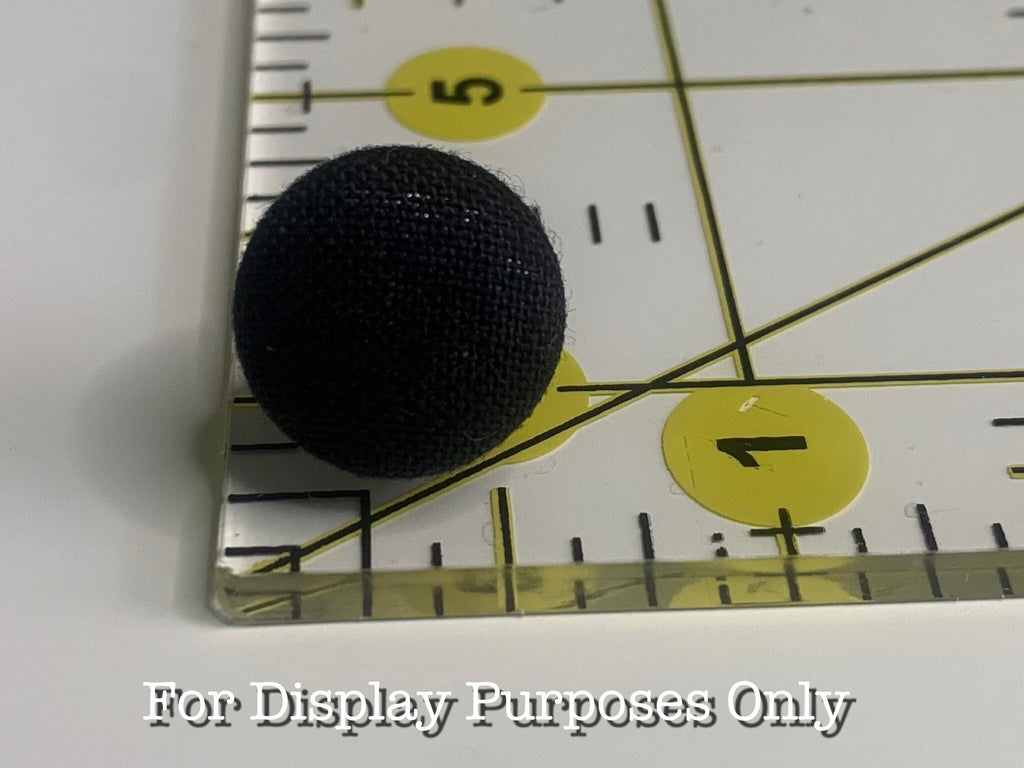 Black textured ball next to a ruler with measurement markings