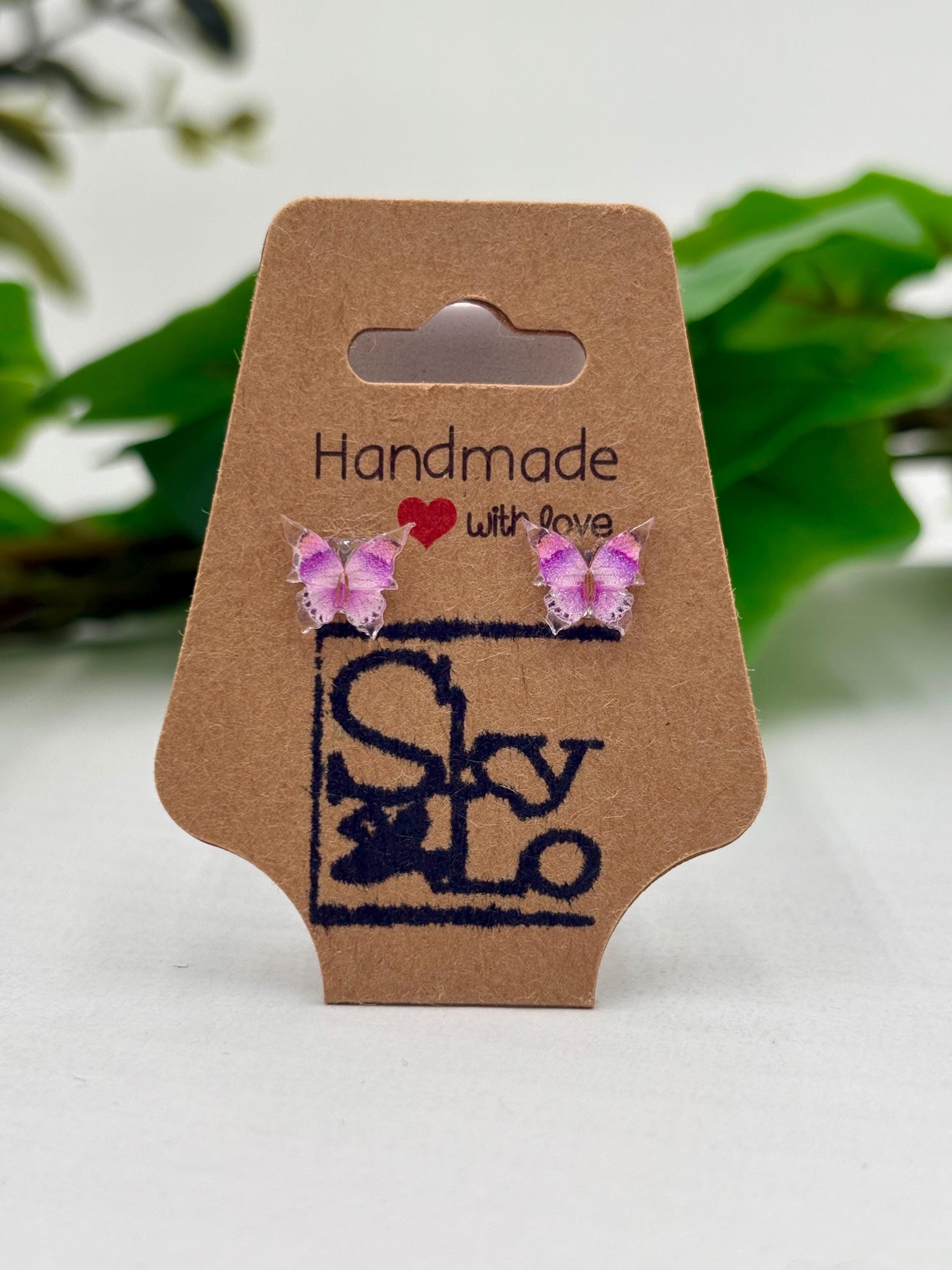 Purple Butterfly earrings on a 'Handmade with Love' branded card with a green leafy background.