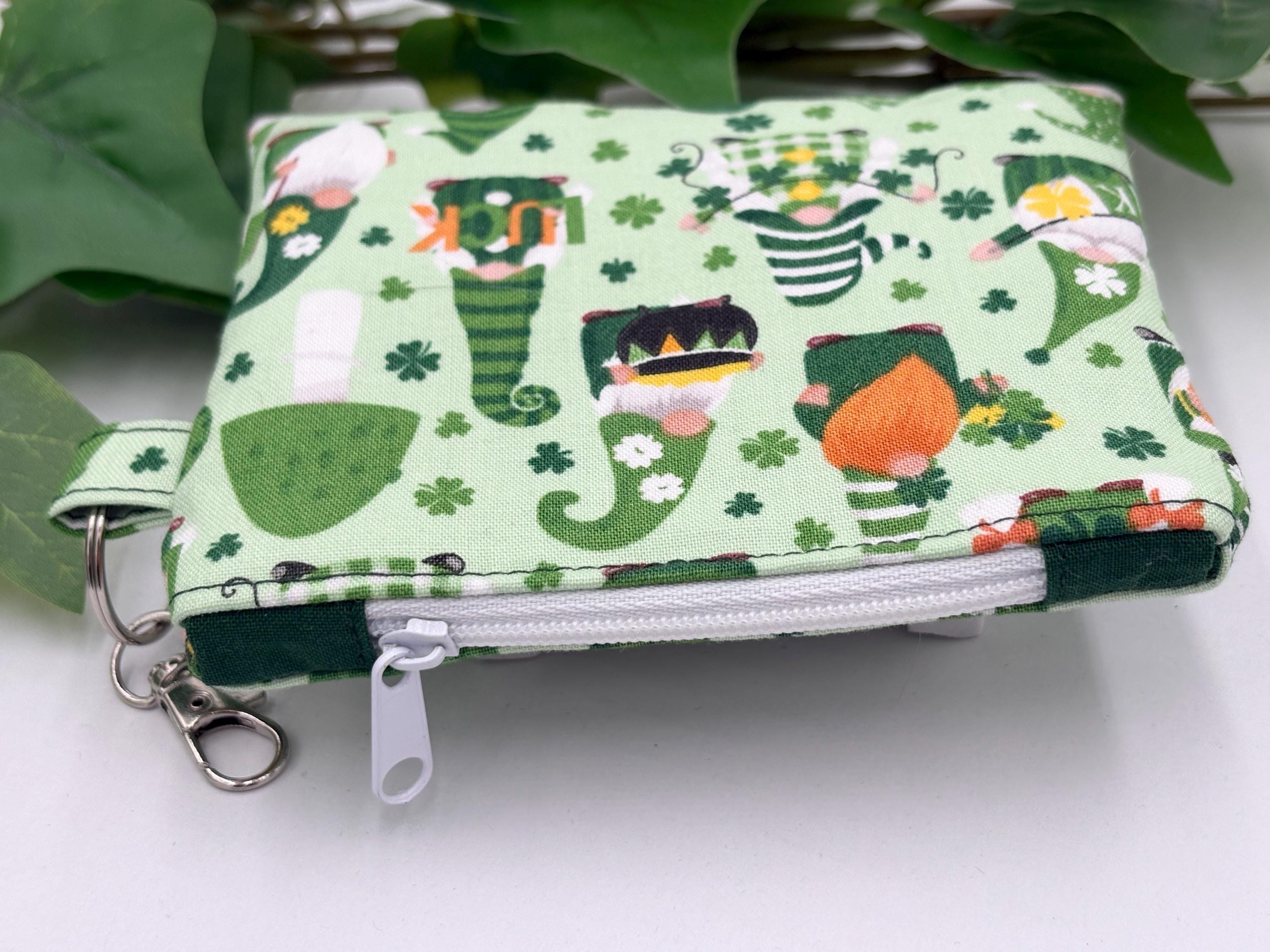 Small coin purse keychain with green st. patrick's day gnomes pattern with a white zipper with dark green zipper tabs on a white background with green leaves