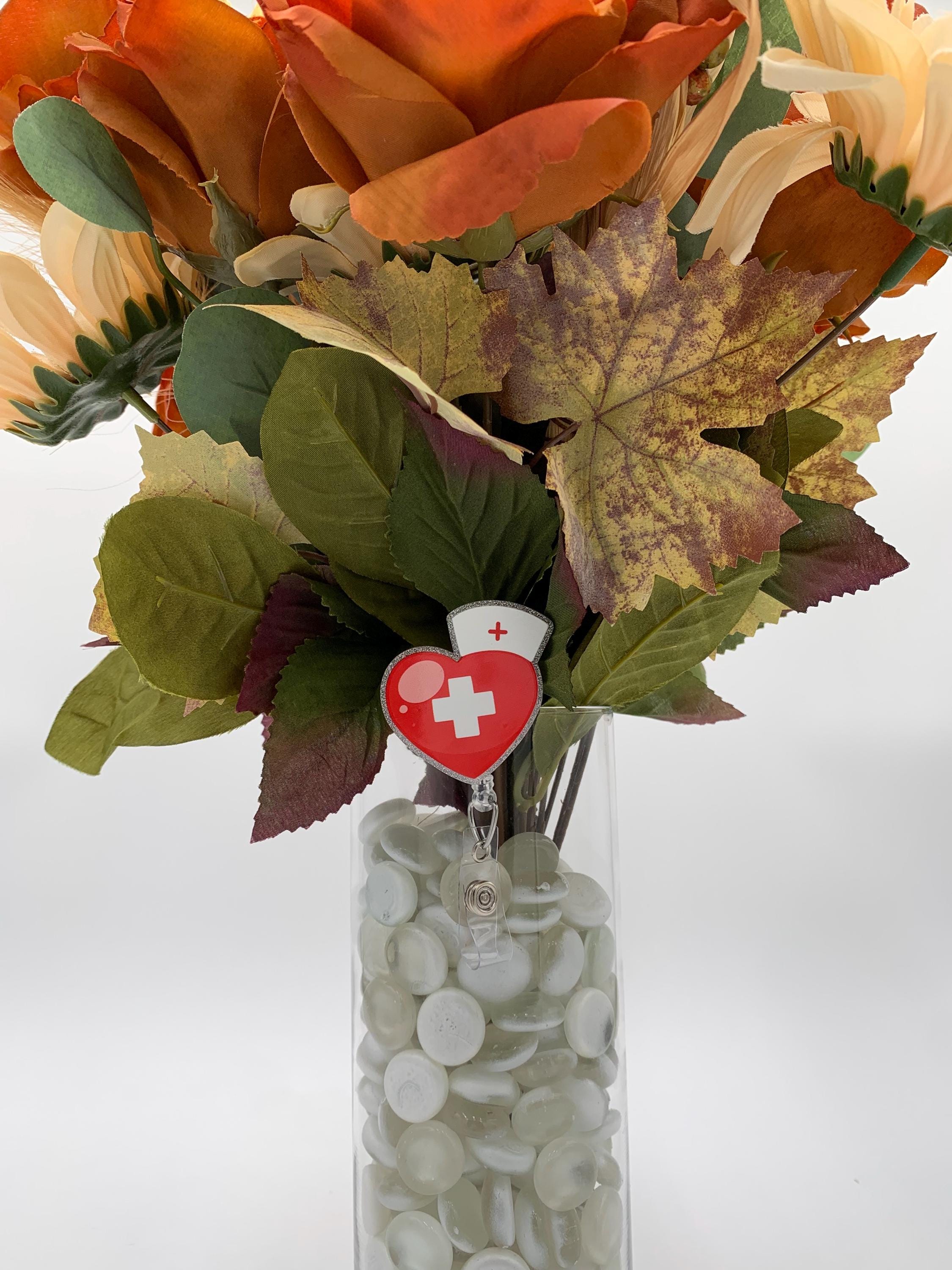 Bouquet of artificial flowers with a heart-shaped badge reel featuring a cross on a white background