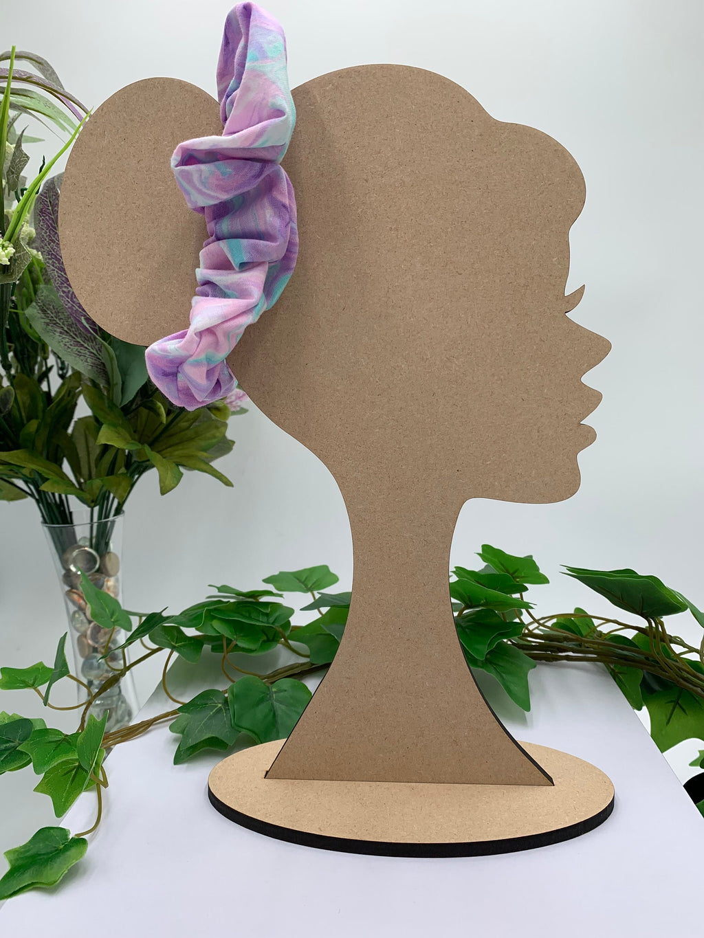 Pastel print scrunchie on a cardboard silhouette of a head with plants in the background
