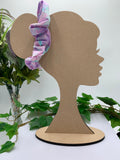 Pastel print scrunchie on a cardboard silhouette of a head with plants in the background