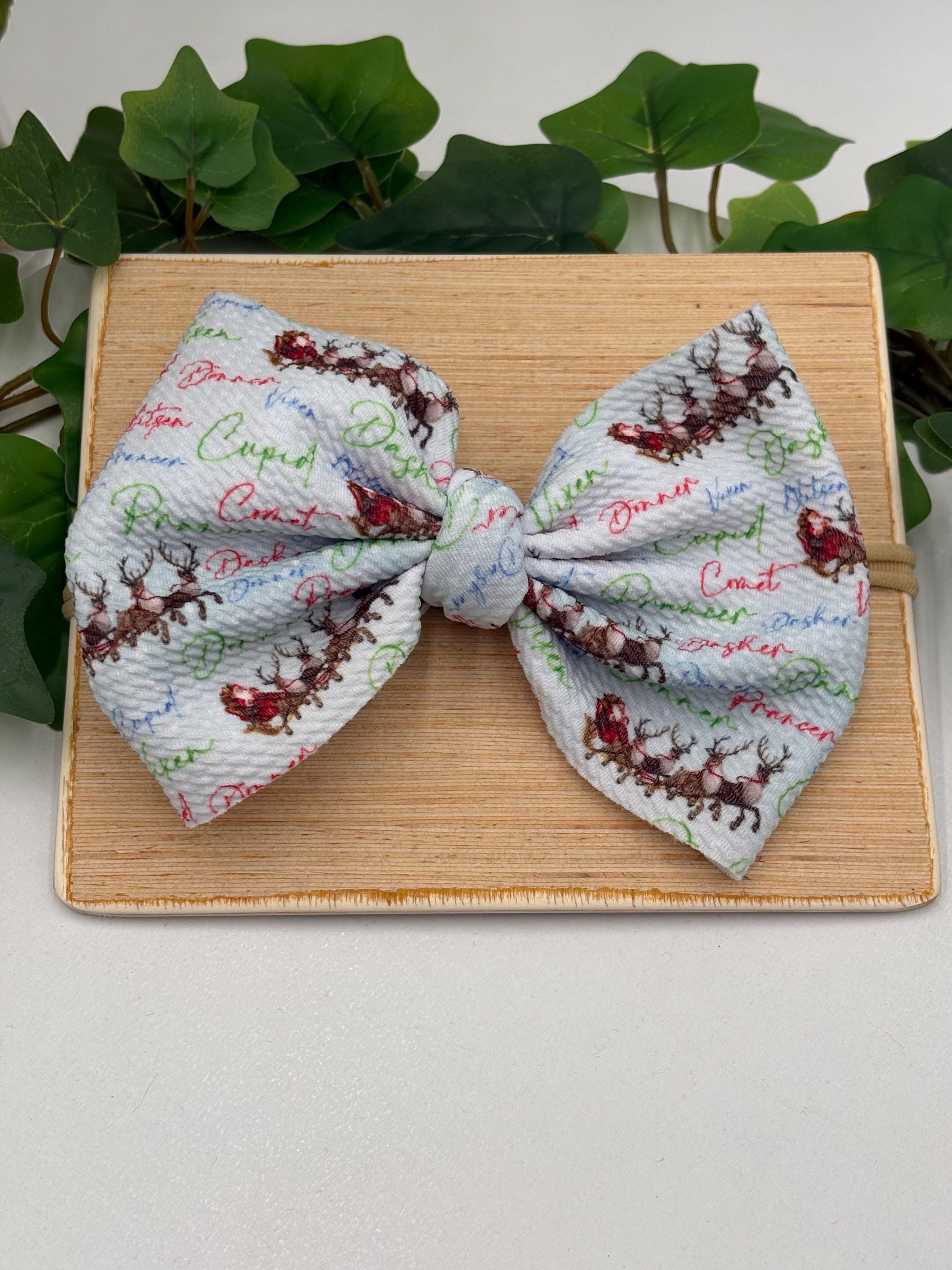Nylon Headband with a decorative christmas themed big bow on a wooden board against a white background