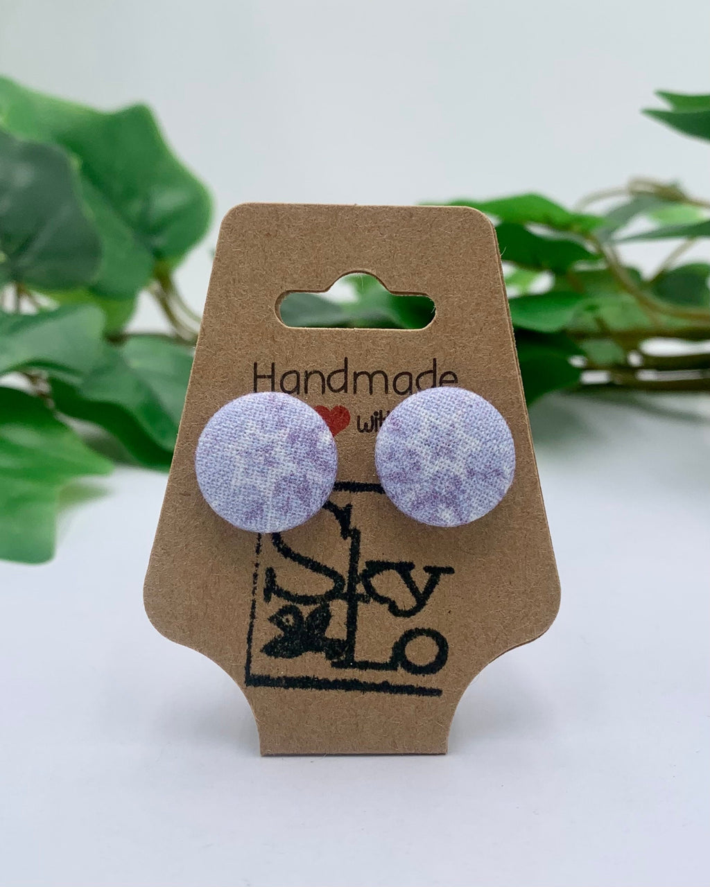 Pair of round earrings on a 'Handmade with Love' card with green leaves in the background