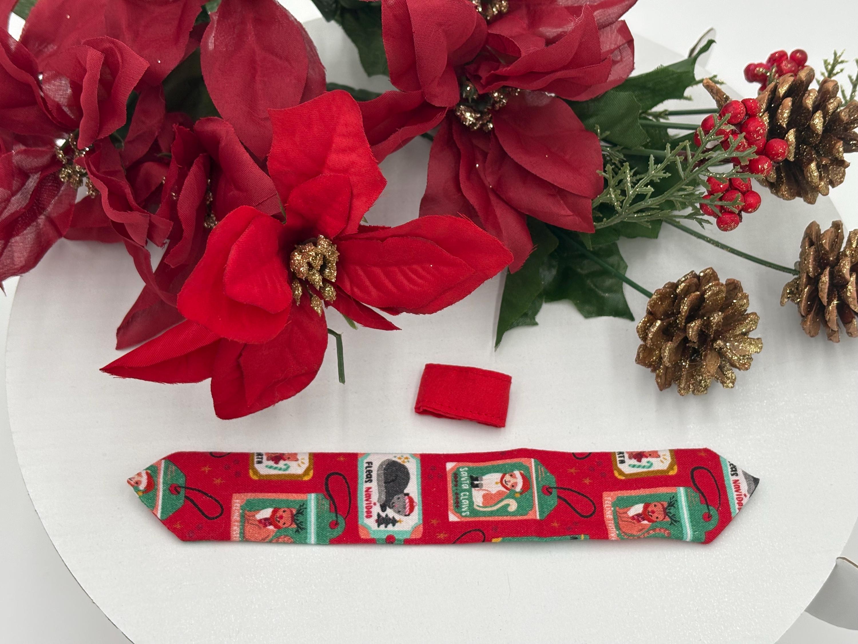 Red Christmas-themed over the collar necktie fully displayed with festive designs on a white background with poinsettias and a pine cone.