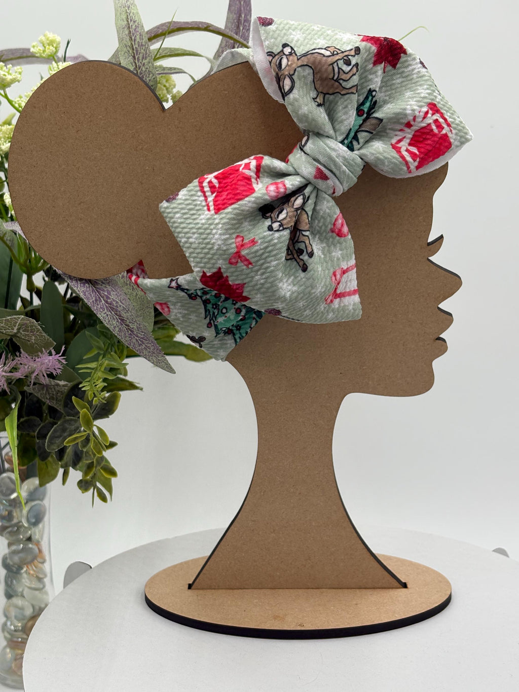 Headband with a decorative christmas themed big bow headband on a mannequin head silhouette against a white background